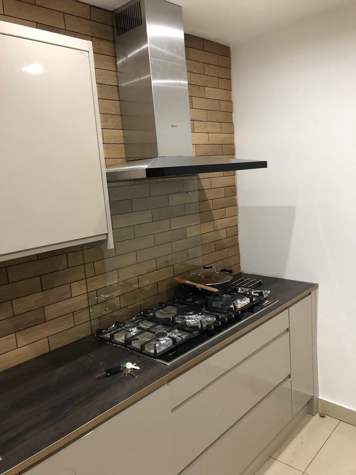 Kitchen hob with extractor fan and tiled backsplash detail